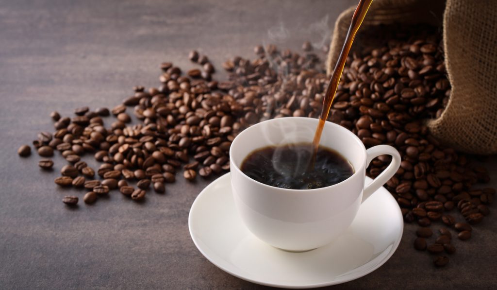 Brewing coffee with spilled over coffee beans in the background 