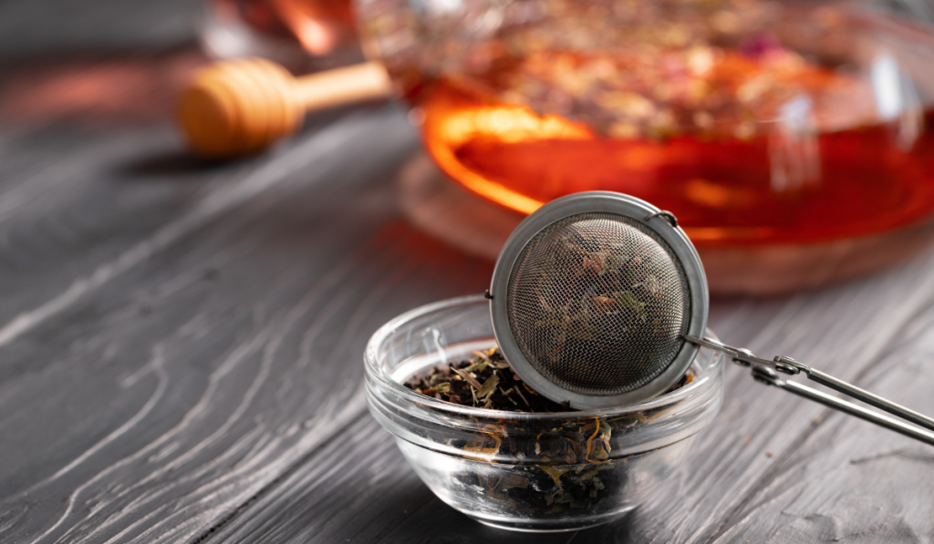 Metal tea strainer on black wooden table