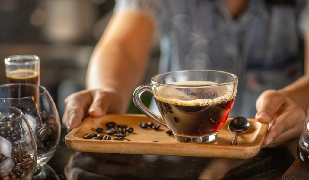 barista serving black drip coffee glass