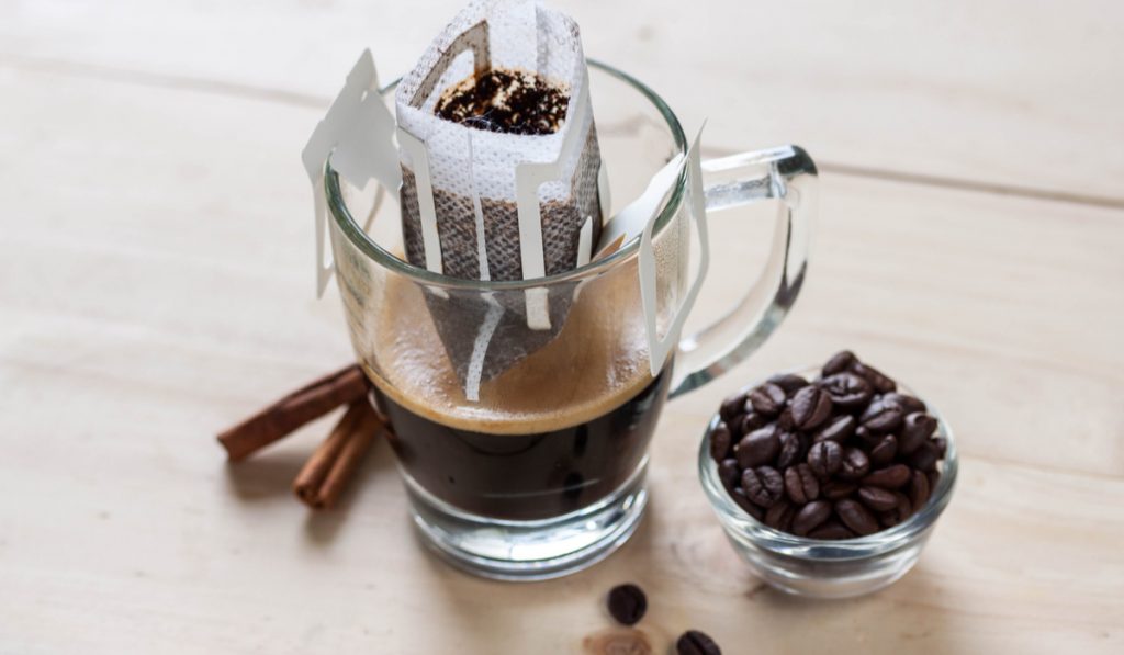 drip brewed coffee and coffee beans on wooden background 