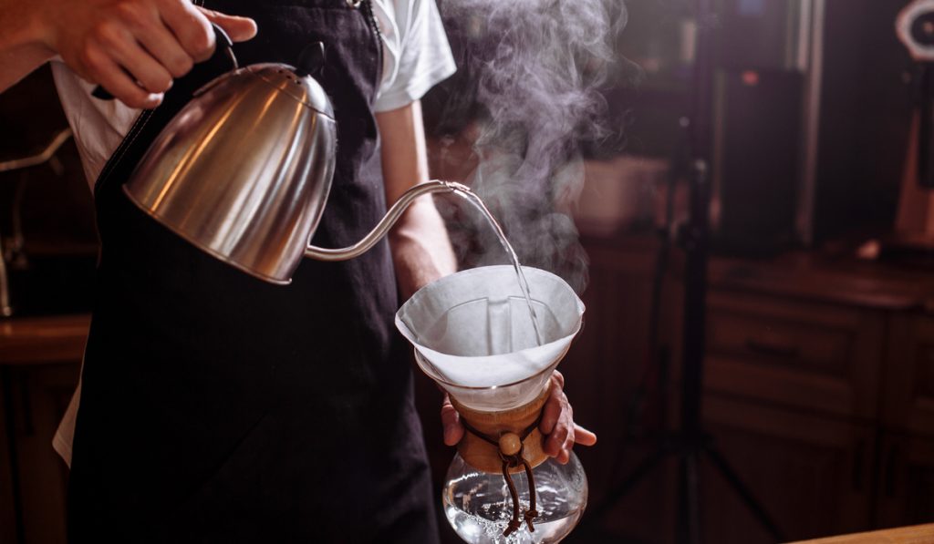 man pouring hot water  coffee bean glass 