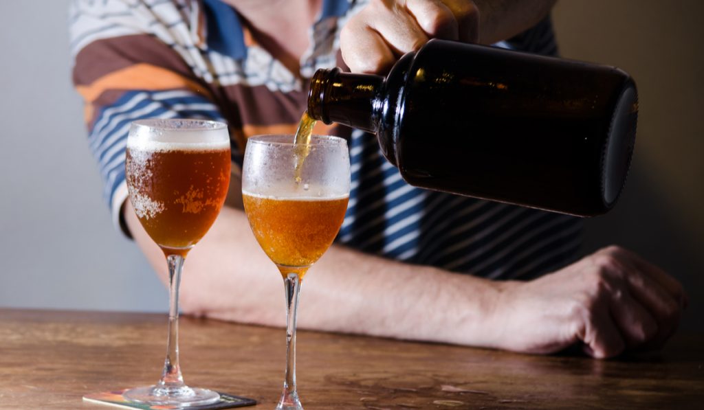 man serving homebrew in glasses with growler