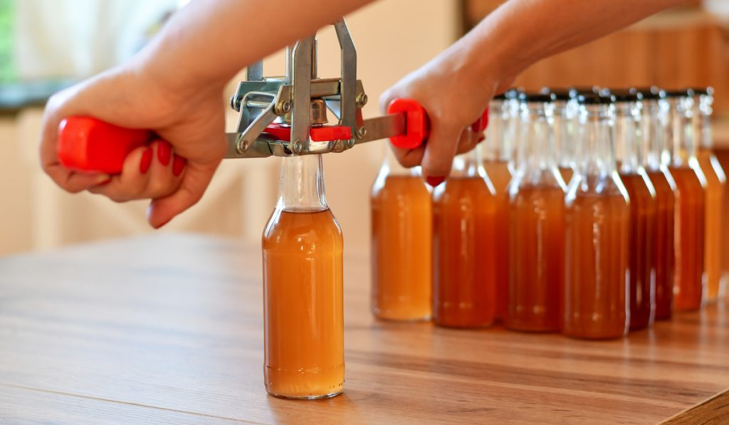 man using hand capper finish product brewed beer bottles 