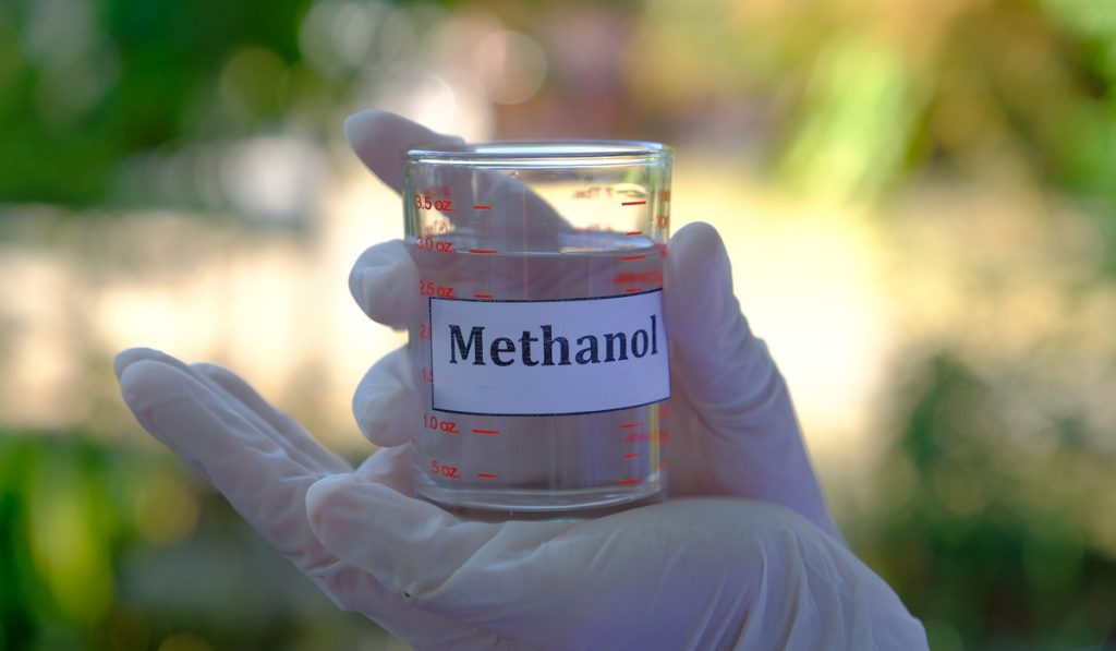 methanol alcohol in a clear measuring glass holding by a man wearing white gloves