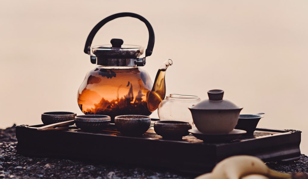 process of brewing tea in nature using a glass teapot.