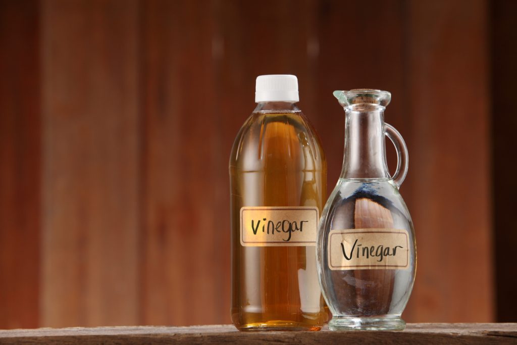 two bottles of vinegar on wooden background 