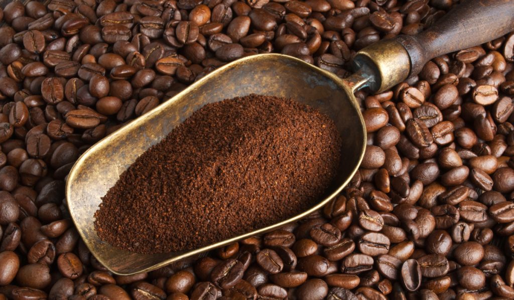 vintage scoop with ground coffee on coffee beans