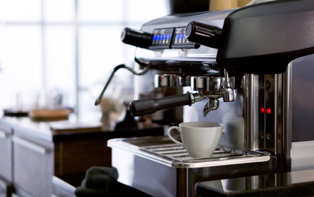 white ceramic cup place on espresso machine