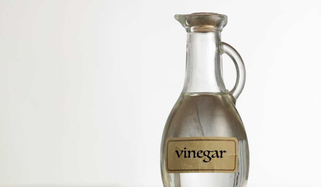 white vinegar in a cork bottle on a white background