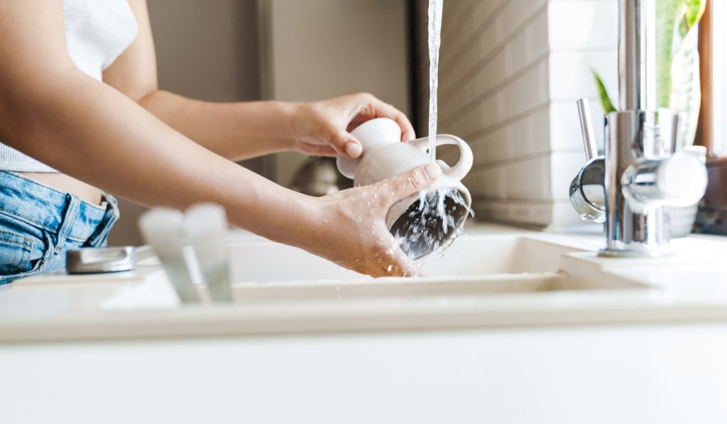 woman washing cup in sink
